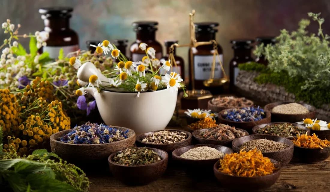 Bowls of dried herbs, petals and flower buds on a wooden table